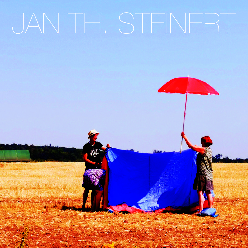 young man wearing shades and a hat with a beard, tattos and ear piercings