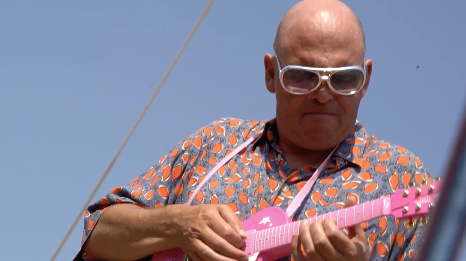 young man wearing shades and a hat with a beard, tattos and ear piercings